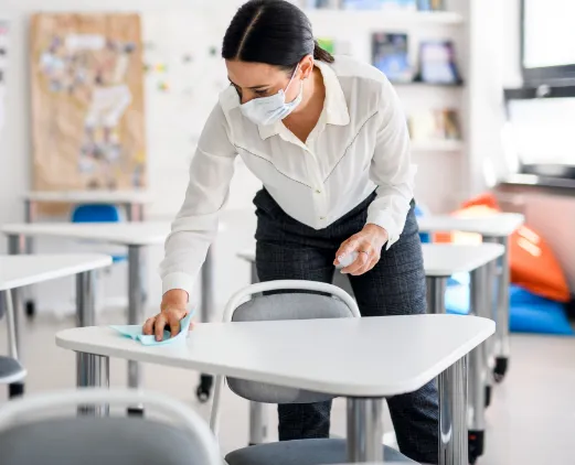 picture of woman in mask cleaning a tabletop